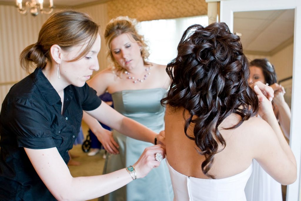 a woman adjusts the corsage of another woman's dress