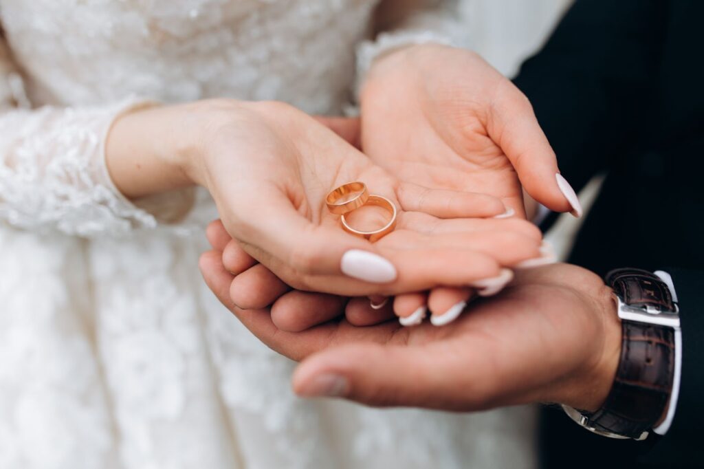 Groom holds bride's hands where are two wedding rings